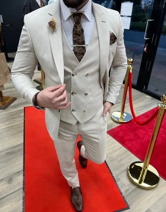 Costume élégant beige avec cravate à motifs.