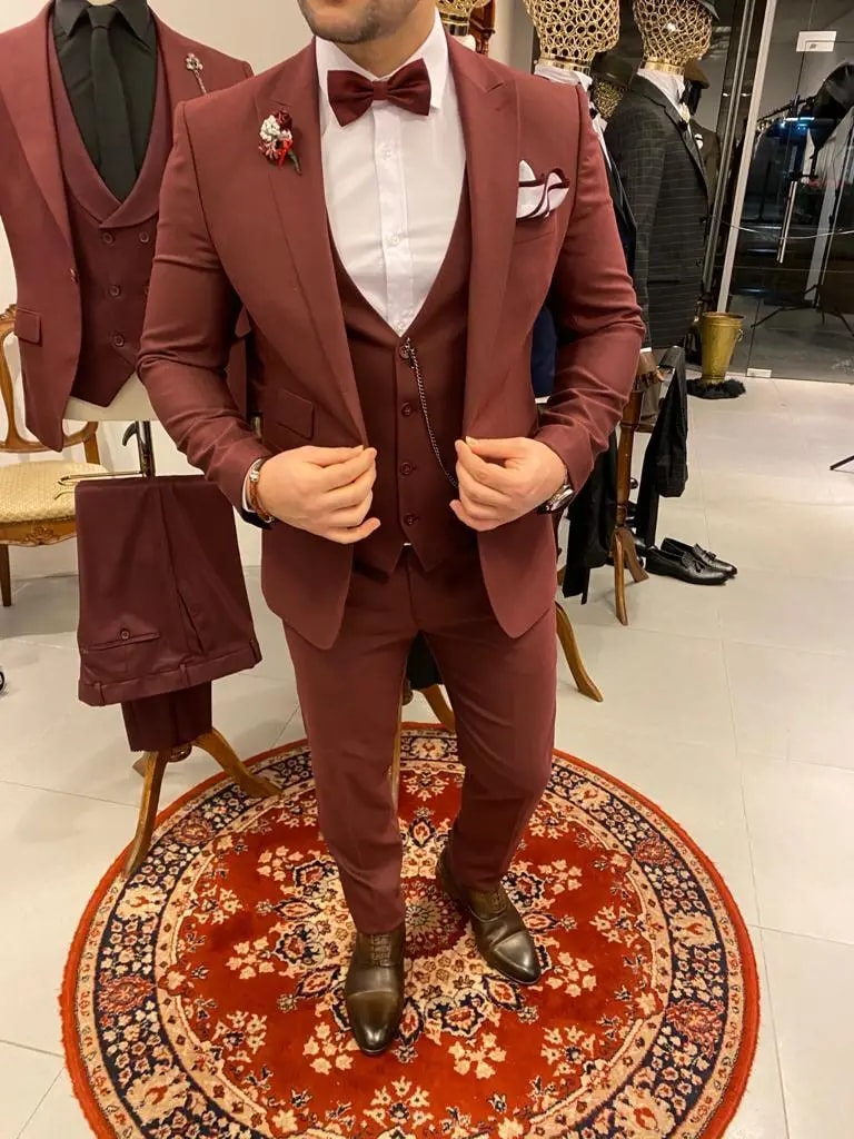 Homme en costume bordeaux avec nœud papillon sur tapis rouge